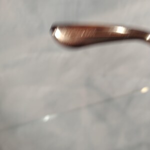 May include: Close-up of a rose gold metal arm of a pair of glasses.