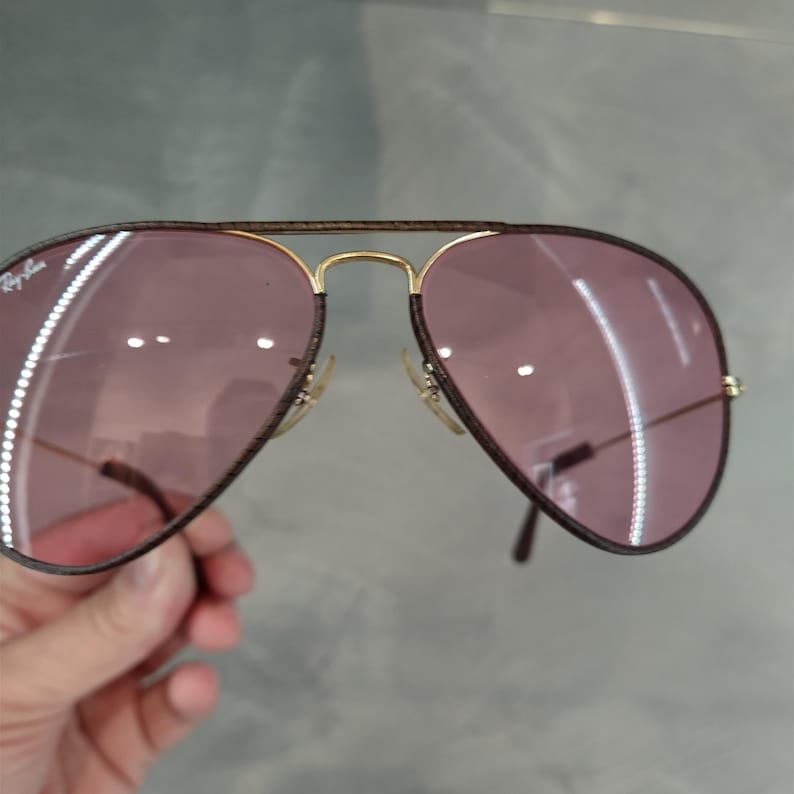 Op de afbeelding: Bruine aviator zonnebril met gouden accenten en roze getinte glazen.