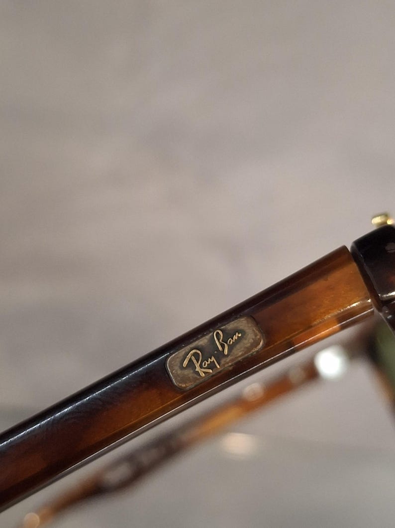 May include: Close-up of Ray-Ban sunglasses with a tortoiseshell pattern. The frame is brown and the Ray-Ban logo is visible on the temple. The glasses have a classic design.