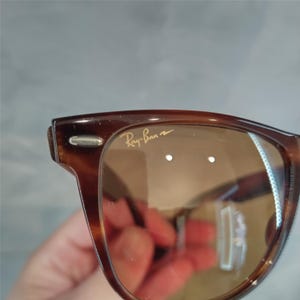 May include: Brown tortoiseshell Ray-Ban sunglasses with brown lenses. The sunglasses have a silver metal accent on the side.