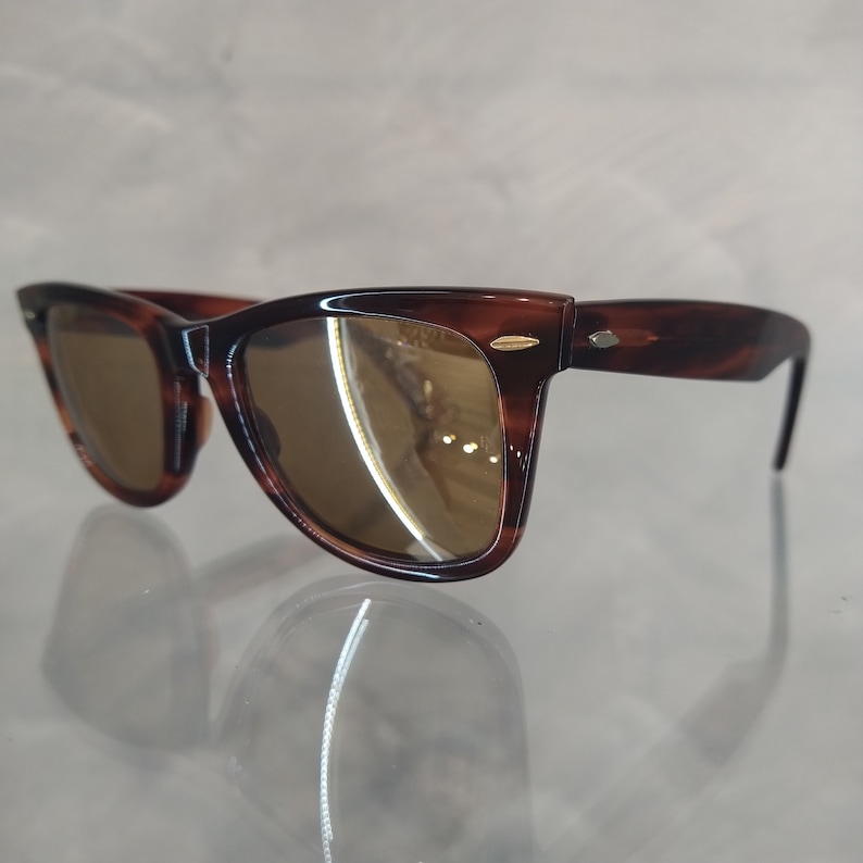 May include: Brown tortoiseshell sunglasses with brown lenses. The sunglasses have a classic, retro style.