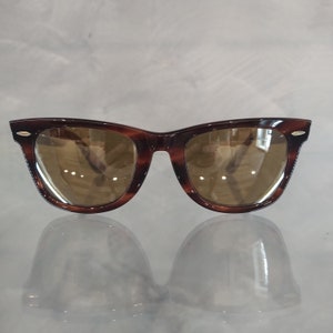 May include: Tortoiseshell sunglasses with brown lenses. The sunglasses have a classic, retro style.