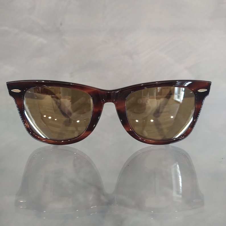 May include: Tortoiseshell sunglasses with brown lenses. The sunglasses have a classic, retro style.