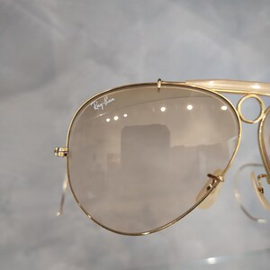 May include: Gold-tone Ray-Ban aviator sunglasses with brown gradient lenses. The sunglasses have a double bridge and a metal frame.