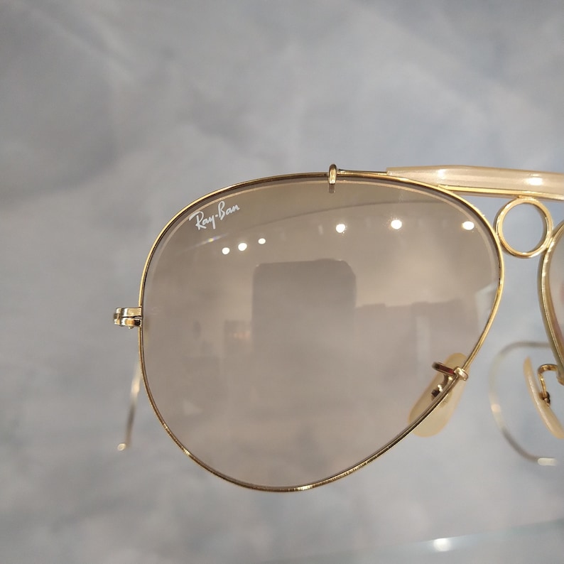 May include: Gold-tone Ray-Ban aviator sunglasses with brown gradient lenses. The sunglasses have a double bridge and a metal frame.