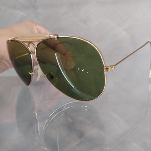 May include: Gold aviator sunglasses with green lenses. The sunglasses have a metal frame and are in good condition.