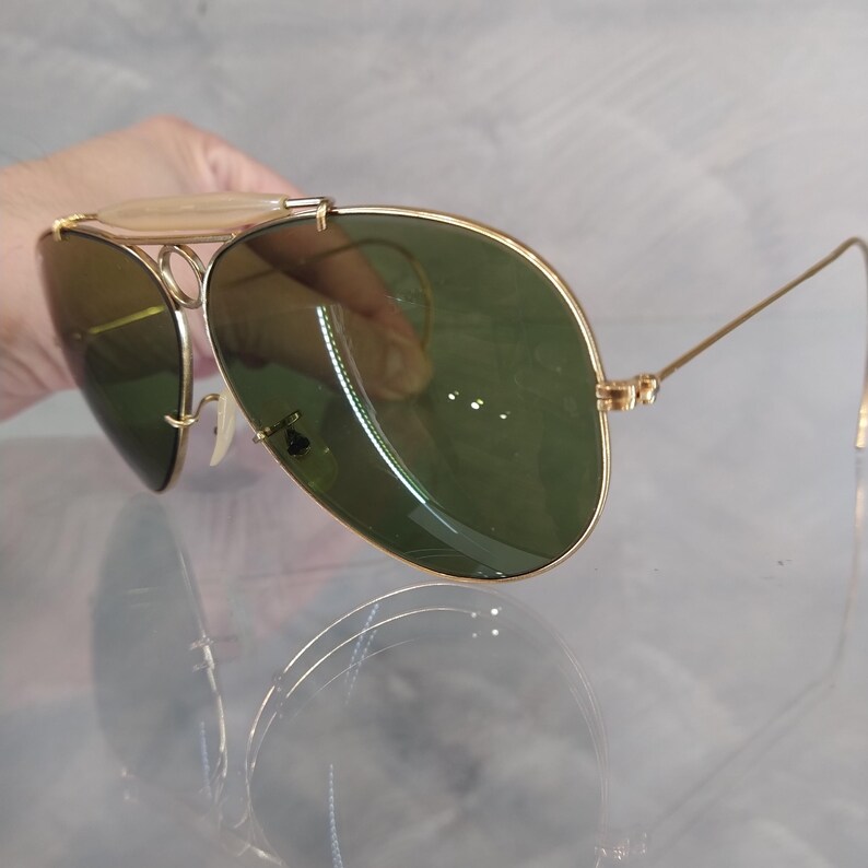 May include: Gold aviator sunglasses with green lenses. The sunglasses have a metal frame and are in good condition.