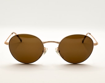 May include: A pair of round, brown sunglasses with a gold metal frame.