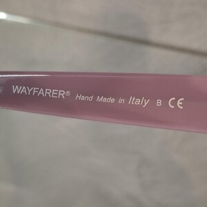 Puede incluir: Primer plano de una patilla de gafas Wayfarer rosa. El texto "WAYFARER&reg; Hand Made in Italy B CE" est&aacute; impreso en blanco en la patilla. La patilla es de color rosa claro liso.