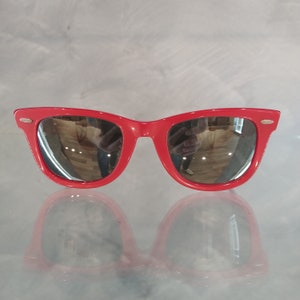 Può includere: Occhiali da sole in plastica rossa con lenti a specchio.