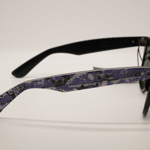 Puede incluir: Gafas de sol negras con un patr&oacute;n de camuflaje morado y gris en las patillas.