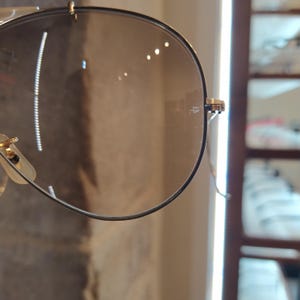 May include: Close-up of a pair of aviator sunglasses with a brown gradient lens. The sunglasses are made of metal and have a gold finish.