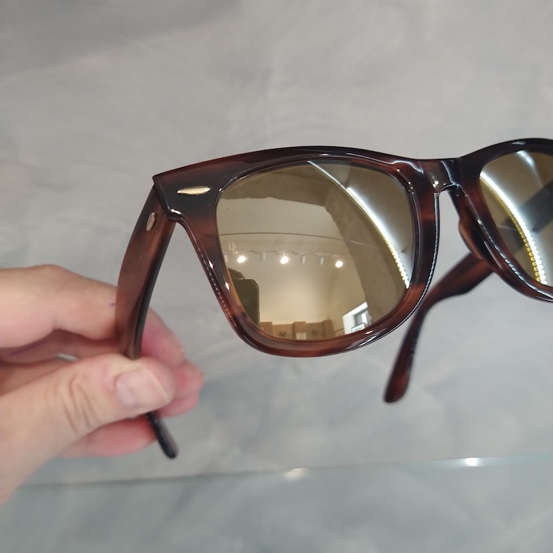 May include: Brown tortoiseshell sunglasses with mirrored lenses. The lenses reflect a light brown colour.