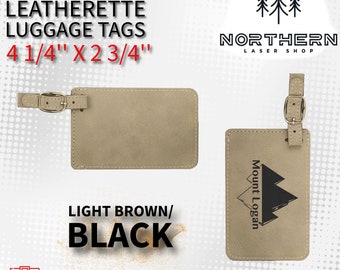 May include: Two light brown leatherette luggage tags with a black strap and metal buckle. The tag on the left is blank. The tag on the right has the text "Mount Logan" in black lettering. The tags are 4 1/4 inches by 2 3/4 inches.