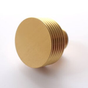 May include: A gold-coloured metal knob with a round top and a ridged base.