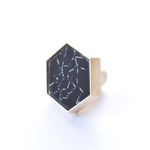 May include: A gold hexagonal cabinet knob with a black marble inlay.