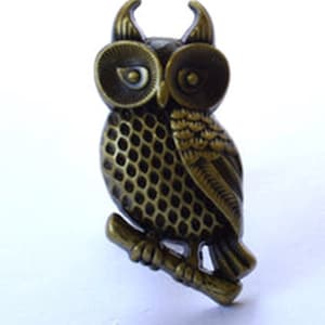 May include: A bronze owl figurine with detailed feathers and large eyes, perched on a branch.