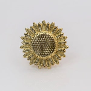 May include: A gold-toned sunflower ring with a textured centre and detailed petals.