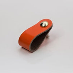 May include: Orange leather cabinet pull with a brown leather backing and a silver metal knob.