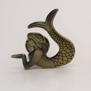 May include: Bronze mermaid figurine with a detailed tail and flowing hair. The mermaid is in a reclining pose, with one arm extended. The tail features a scale pattern. The figurine is likely made of metal and has an antique finish.