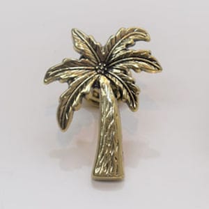 May include: A gold palm tree ornament with a detailed design. The palm tree is made of metal and has a textured finish.