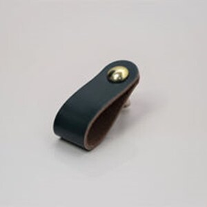 May include: A dark blue leather cabinet pull with a brown leather backing and a gold metal knob.