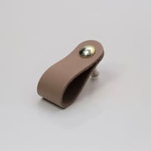 May include: A light pink leather cabinet pull with a gold metal knob.