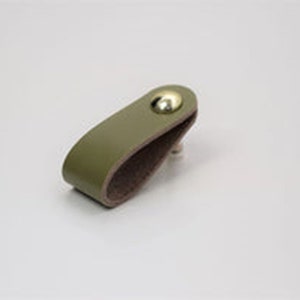 May include: A green leather cabinet pull with a gold metal knob.