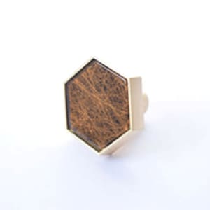 May include: A hexagonal cabinet knob with a wood inlay and a gold metal frame.