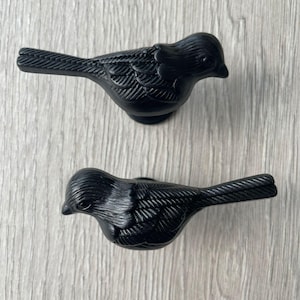 May include: Two black metal bird-shaped drawer pulls. The birds have detailed wings and a textured finish.