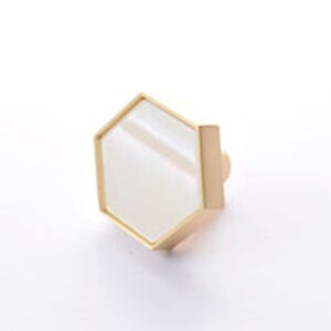 May include: A gold hexagonal cabinet knob with a white centre.
