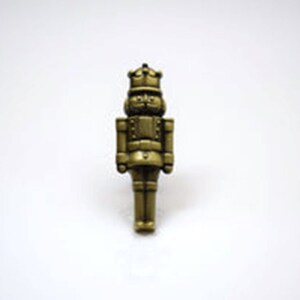 May include: A gold-coloured nutcracker figurine with a crown on its head. The nutcracker is standing upright with its arms at its sides.