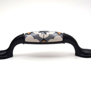 May include: Black cabinet pull with a white ceramic insert featuring a geometric pattern in shades of grey and orange.
