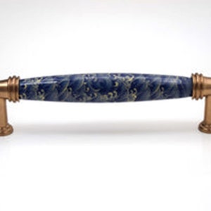 May include: A blue and gold ceramic cabinet pull with a wave pattern. The pull has a rectangular shape and is approximately 5 inches long.