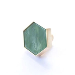 May include: A hexagonal cabinet knob with a green, marbled, glass insert and a gold metal frame.