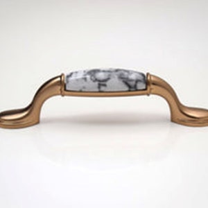 May include: A gold cabinet knob with a white marble-patterned top.