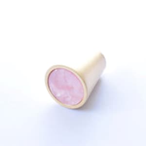 May include: A gold cone-shaped cabinet knob with a pink and white marbled inlay.