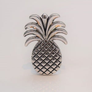 May include: A silver napkin ring shaped like a pineapple. The ring features a textured pineapple design.