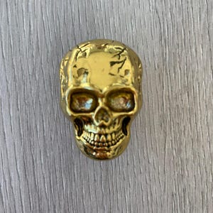 May include: A gold-coloured skull-shaped decorative knob.