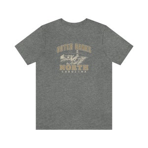 Pode incluir: Uma camiseta cinza mesclada com um gr&aacute;fico vintage de um farol e o texto "Outer Banks North Carolina".