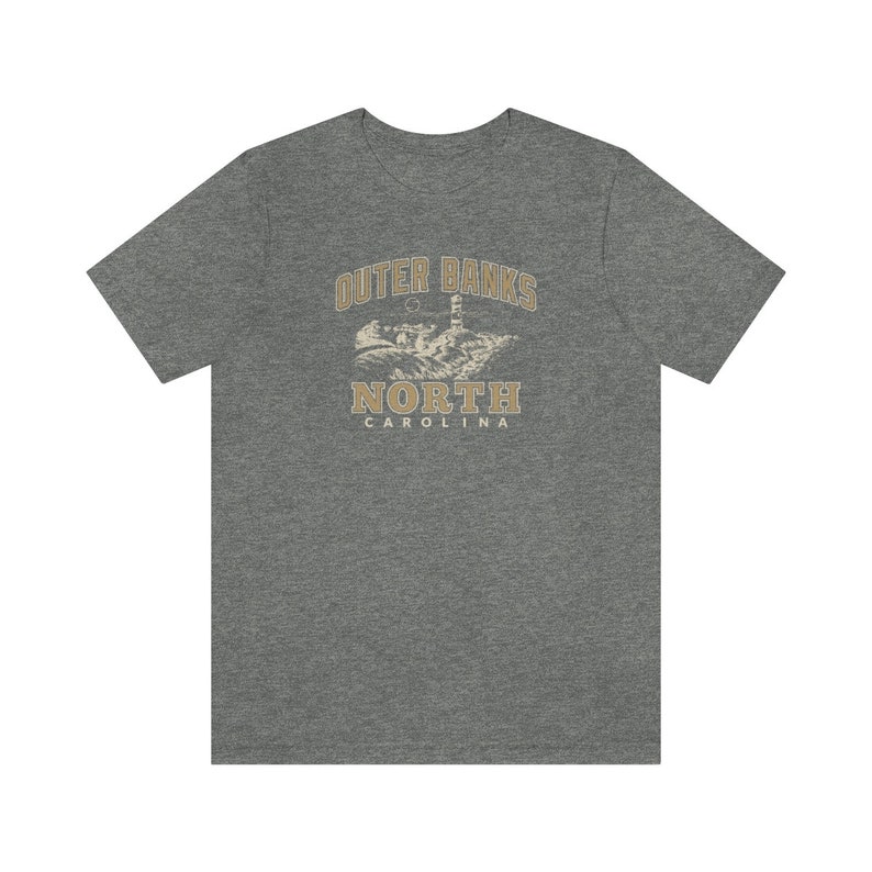 Pode incluir: Uma camiseta cinza mesclada com um gr&aacute;fico vintage de um farol e o texto "Outer Banks North Carolina".