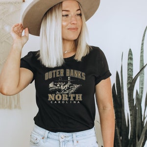 Camiseta feminina unissex de manga curta com estampa de farol na praia de Outer Banks, Carolina do Norte, ideal para férias ou brunch. imagem 4