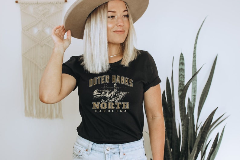 Camiseta feminina unissex de manga curta com estampa de farol na praia de Outer Banks, Carolina do Norte, ideal para férias ou brunch. imagem 4