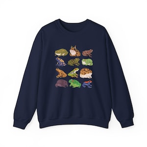 Puede incluir: Una sudadera azul marino con un estampado gr&aacute;fico de diferentes ranas en varios colores y patrones.