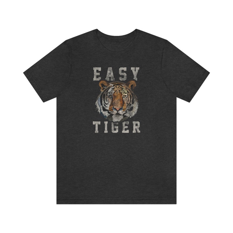 K&ouml;nnte beinhalten: Ein dunkel-melierter grauer T-Shirt mit einem abgenutzten wei&szlig;en Grafikdruck eines Tigergesichts und dem Text "EASY TIGER".