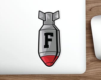 Puede incluir: Una pegatina con un diseño de bomba de dibujos animados. La bomba es principalmente gris con un contorno negro, una punta roja y la letra "F" en negro. La pegatina tiene un fondo blanco.