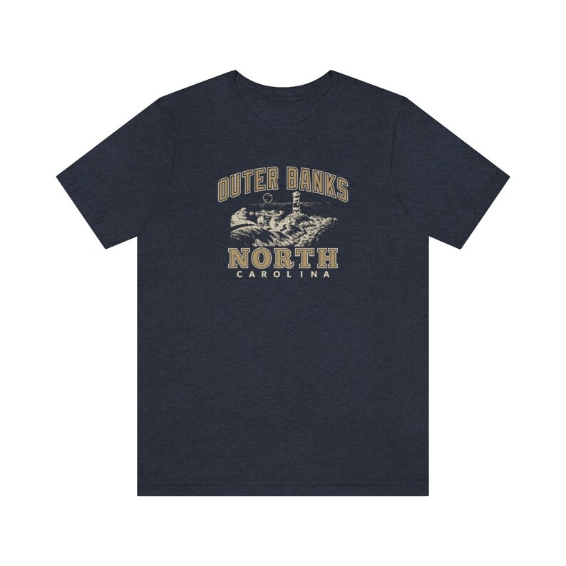 Pode incluir: Uma camiseta azul marinho com um gr&aacute;fico vintage de um farol e o texto "Outer Banks North Carolina".
