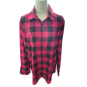 May include: A red and black plaid button-down shirt. The long-sleeved shirt is displayed on a mannequin. The shirt has a classic collar and buttoned cuffs. The plaid pattern is made up of large, evenly spaced squares.