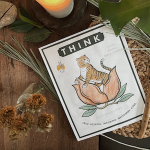 May include: A printable colouring page featuring a tiger sitting on a flower. The page includes the text "THINK", "FLORA", "FAUNA", "BIBLE VERSES", "COCONUT & HUSKS", "A MINI COLOUR + COPY", "TRUE. HELPFUL. INSPIRING. NECESSARY. KIND."