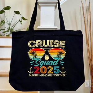 May include: Black tote bag with a colorful graphic that reads "CRUISE Squad 2025" with sunglasses, palm trees, and anchors. The bag is made of a durable material and has two black handles. The text "MAKING MEMORIES TOGETHER" is also included.